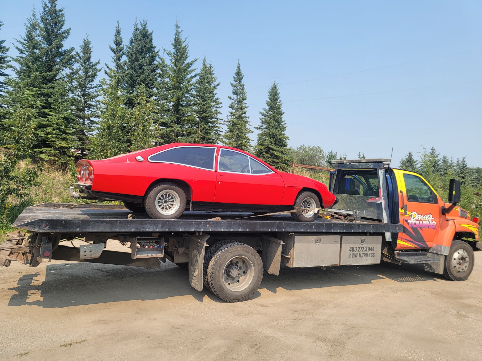 Red classic car transported on flatbed truck near Calgary